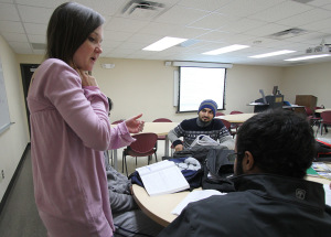 Sultan Alanizi and Riyadh Al Saho ask Brittany Norman, English teaching assistant, for help with English workbooks in the Intensive English Language Institute conversation and grammar class Tuesday. Photo by Lauren Roberts