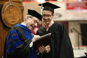 Retiring university President Jesse Rogers signs a copy of Sunwatcher magazine for Wichitan Editor Ethan Metcalf at Midwestern State University graduation, May 16, 2015 at the Kay Yeager Coliseum. Photo by Francisco Martinez