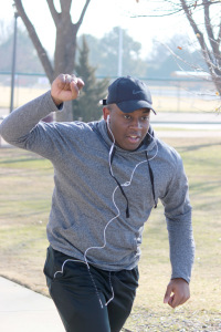 Keith Ngondo, nursing freshman, crosses the finish line first with his fist up at the one mile Cookie Dash set by the University Programming Board at Sikes Lake, Jan. 23, 2016. Photo by Francisco Martinez