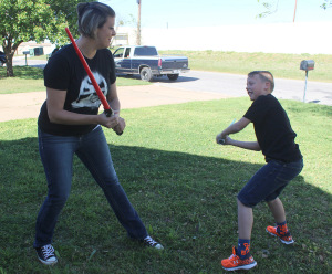 Jacklyn York, mass communication junior, and her son Braiden York play a game of light saber battle in the front lawn. Photo by Rachel Johnson