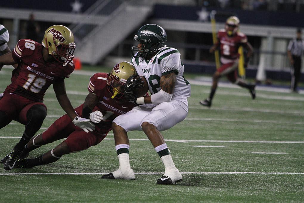 Eastern New Mexico running back Jordan Wells is tackled by Marqui Christian, criminal justice junior, at the  Midwestern State University v. Eastern New Mexico game at AT&T Cowboys Stadium in Arlington, Sept. 20, 2014. Photo by Lauren Roberts