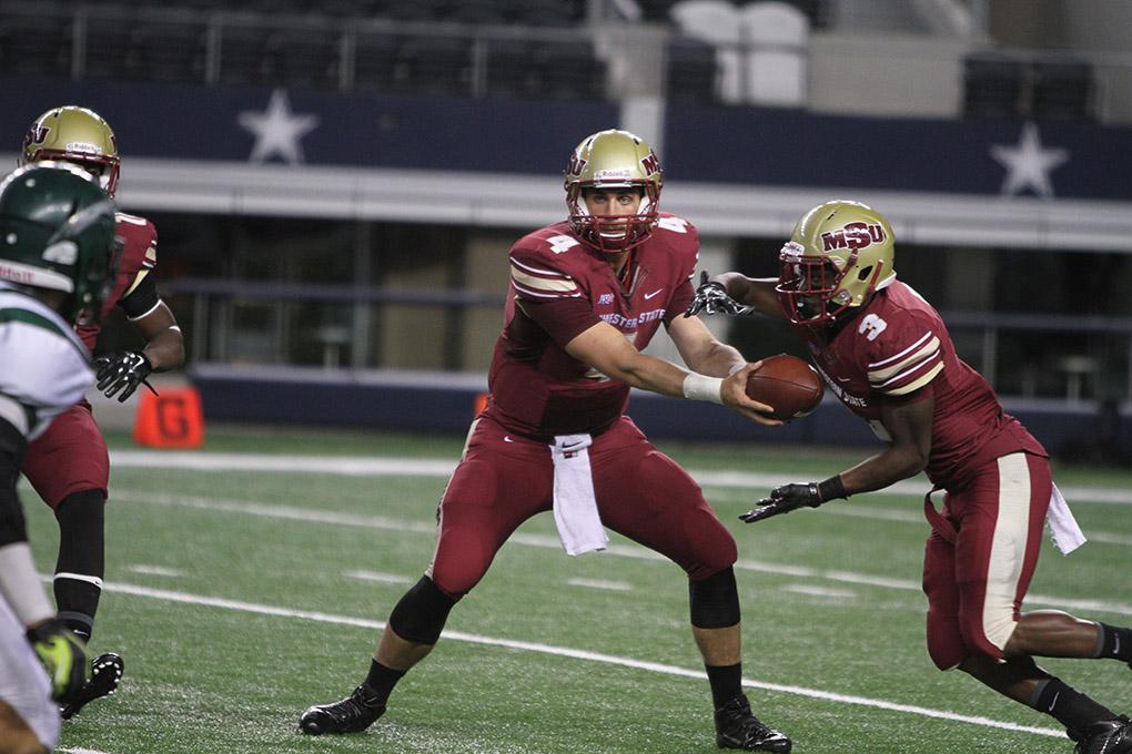 Quaterback Jake Glover, accounting senior, hands the ball of to running back Chauncey Harris, criminal justice senior, at Midwestern State University v. Eastern New Mexico game at AT&T Cowboys Stadium in Arlington, Sept. 20, 2014. Photo by Lauren Roberts