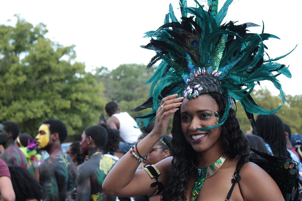 Rainah Winston, biology and chemistry senior, fixes her head piece while she dancees during the 2015 CaribFest Parade, Sept. 25. Photo by Kayla White