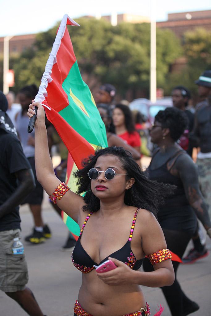 Orianna Law, nursing sophomore, holds a flag while she dances along the truck blasting festive Caribbean music in the CaribFest Parade, Sept. 25. Photo by Francisco Martinez