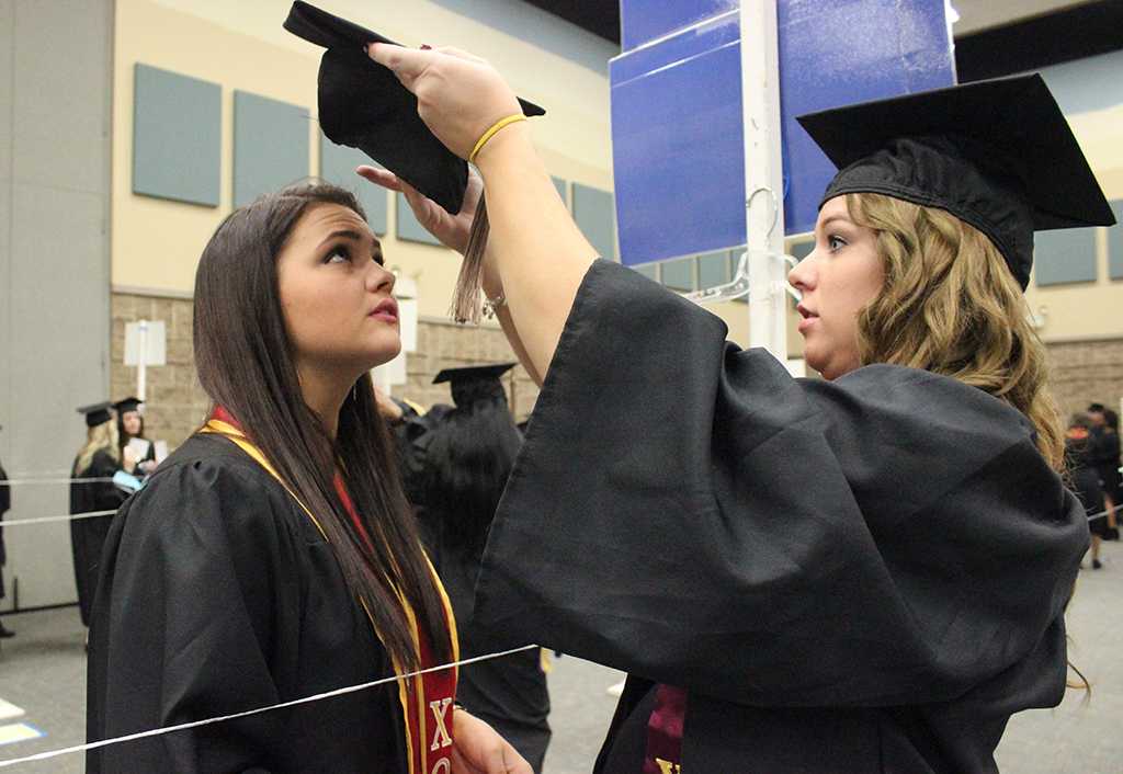 Kailey Tull, kinesiology, puts on Alexis Morton's, accounting, cap while waiting in the MPEC before Commencement Ceremony held in the Kay Yeager Coliseum, Dec. 12, where 440 crossed the stage. Photo by Rachel Johnson