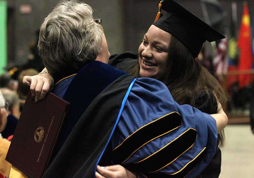 Astri Burgos, nursing, hugs her professors as she heads back to her seat after recieving her diploma case in the Kay Yeager Coliseum, Dec. 12. Photo by Rachel Johnson