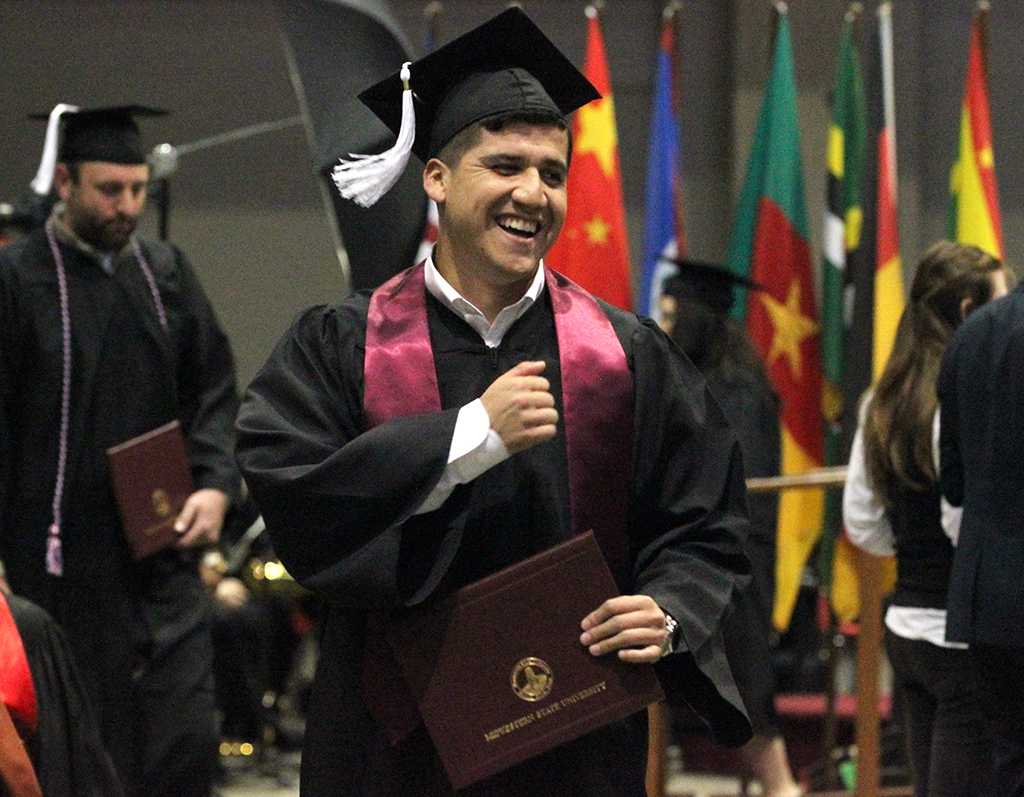 Francisco Espinoza, bachelor of applied arts and science, pounds his chest after waving to friends who were graduates as well int he Kay Yeager Coliseum, Dec. 12. Photo by Rachel Johnson