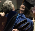 Astri Burgos, nursing, hugs her professors as she heads back to her seat after recieving her diploma case in the Kay Yeager Coliseum, Dec. 12. Photo by Rachel Johnson