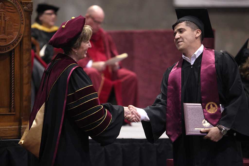 Suzanne Shipley, university president, congratulates Francisco Espinoza, applied arts and sciences, as he walks across the stage at the Commencement Ceremony in Kay Yeager Coliseum Dec. 12, 2015