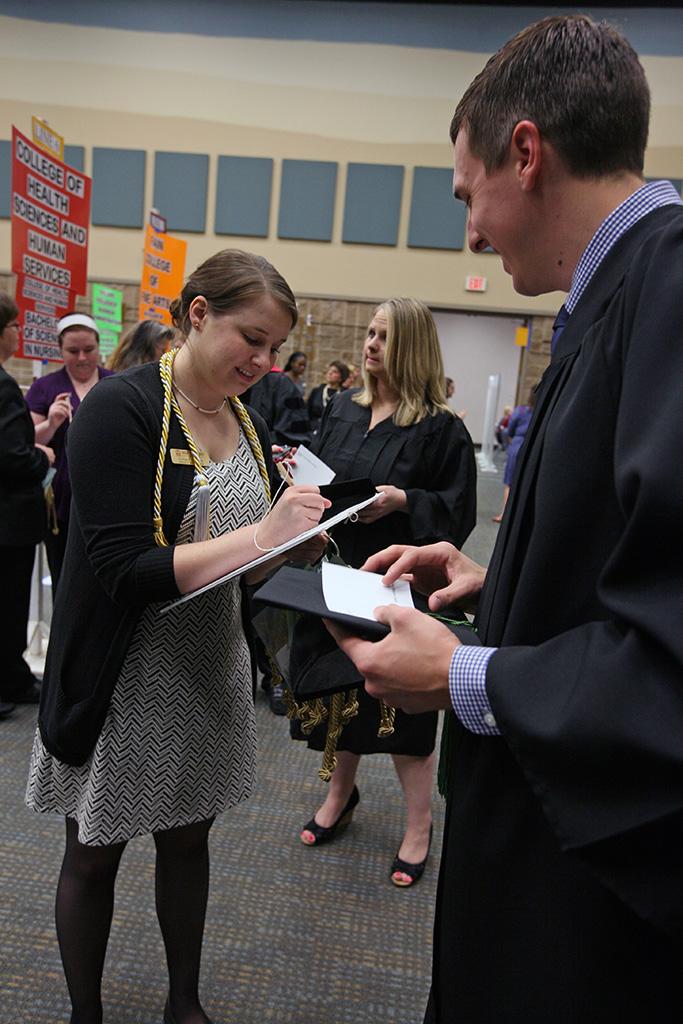 Ginger Bartush, registrar assistant, helps Robert Jacob, radiologic science, find his spot before the ceremony at the Midwestern State University graduation, May 16, 2015 at the Kay Yeager Coliseum. Photo by Rachel Johnson