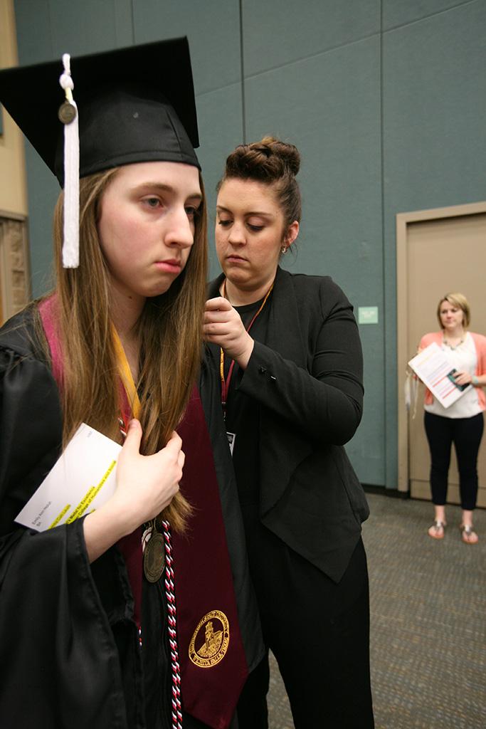 Kayla Brixey, registrar assistant, helps fix Emmily Ann Holub's, political science, gown before the ceremony at Midwestern State University graduation, May 16, 2015 at the Kay Yeager Coliseum. Photo by Rachel Johnson