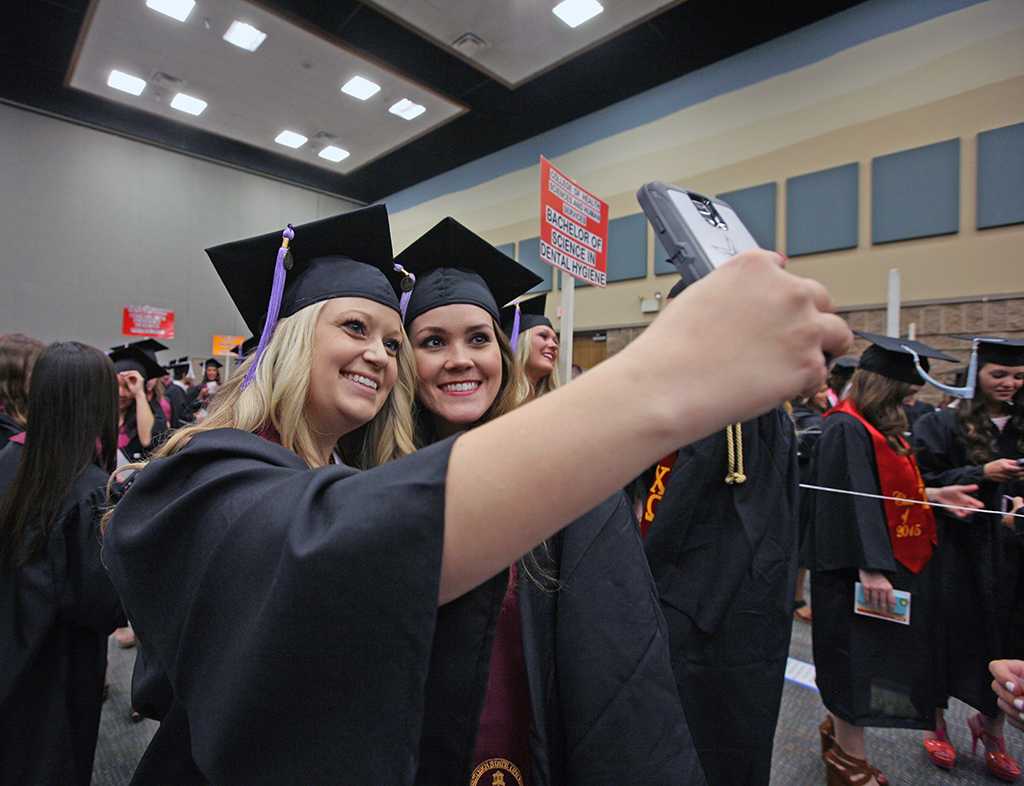 Meagan Sims, dental hygene, and Devon Jones, dental hygene, take a selfie before the ceremony at Midwestern State University graduation, May 16, 2015 at the Kay Yeager Coliseum. Photo by Rachel Johnson