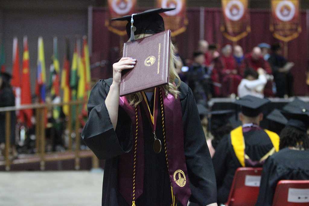 Haley Reid, special education, hides her face from the cameras as she walks back to her chair at Midwestern State University graduation, May 16, 2015 at the Kay Yeager Coliseum. Photo by Rachel Johnson
