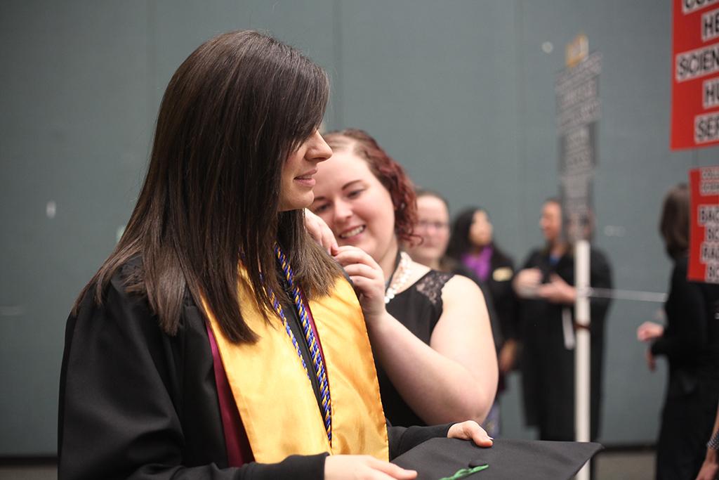 Kristie Coomer, radiologic sciences graduate getting her cords pinned on her sleeve at the Midwestern State University graduation, Fall 2016. Photo by Jeanette Perry.