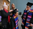 Barbara Lunce and Linda Knox help Lucia Treja with her mortar board. Photo by Bradley Wilson