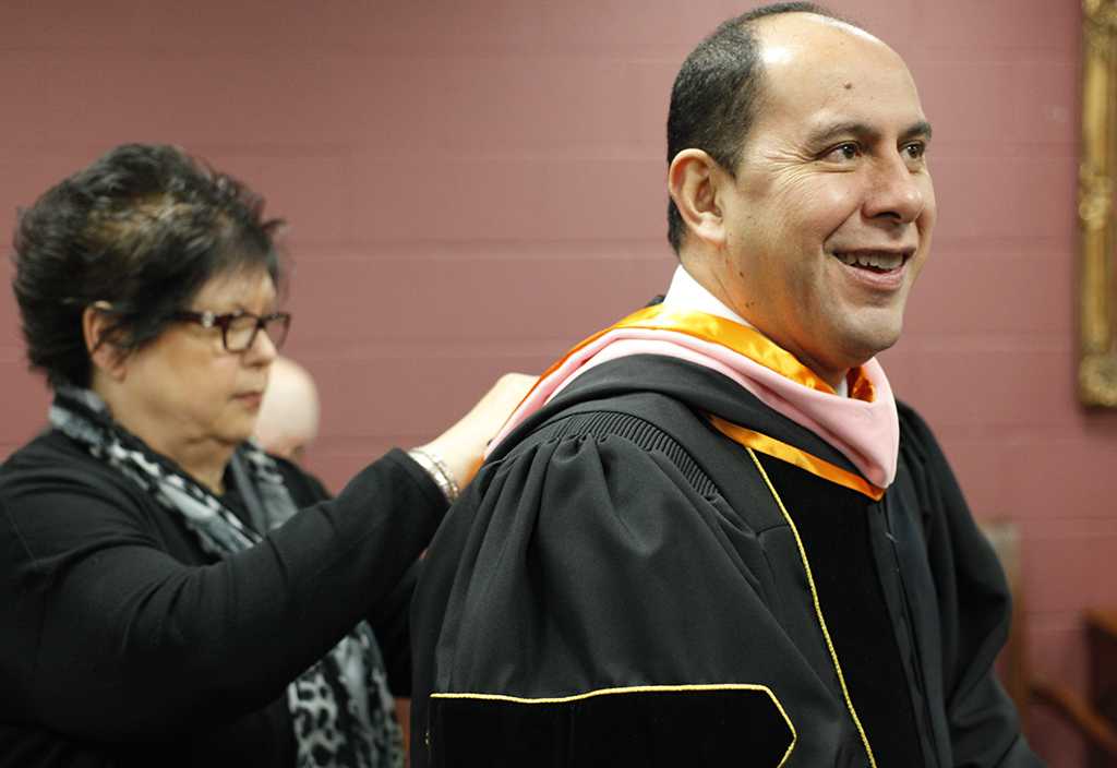 Treva Clifton, president assistant, helps Martin Camacho, dean of fain college of fine arts, with his sashes before MSU's commencement ceremony at Kay Yeager Coliseum. Saturday Dec. 16, 2017. Photo by Francisco Martinez