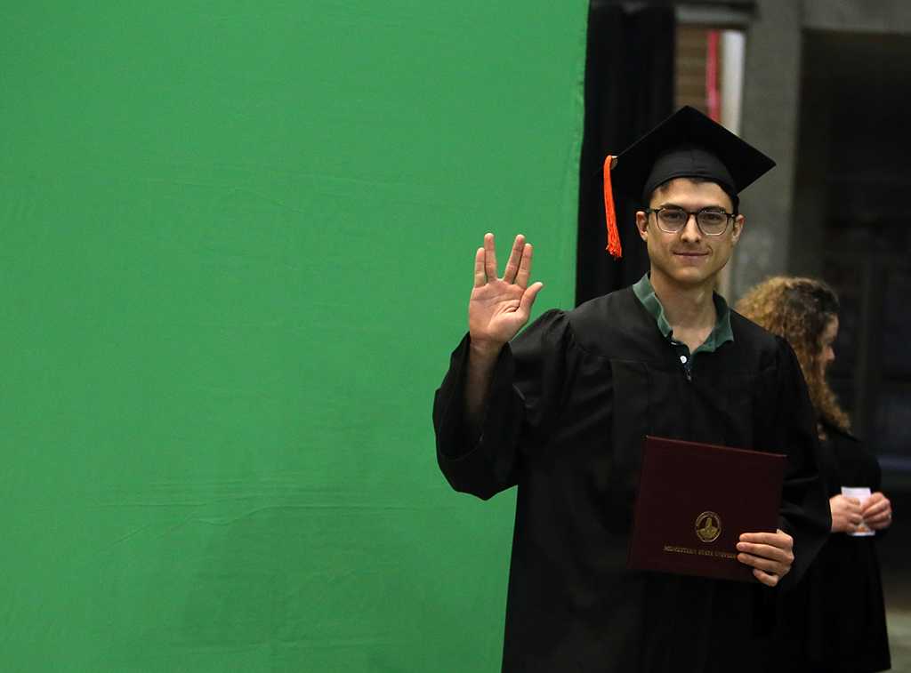 Michael Olaya pauses for a photo after graduation, Dec. 16, 2017. Photo by Bradley Wilson