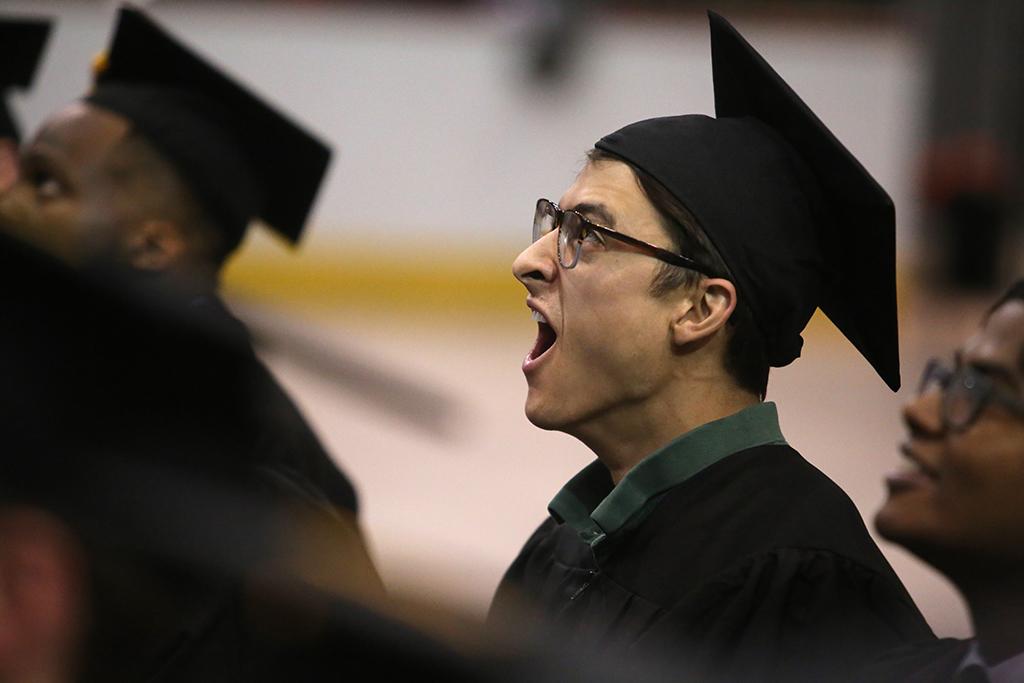Michael Olaya, in the last row of graduates, yawns before the ceremony ends at graduation, Dec. 16, 2017. Photo by Bradley Wilson