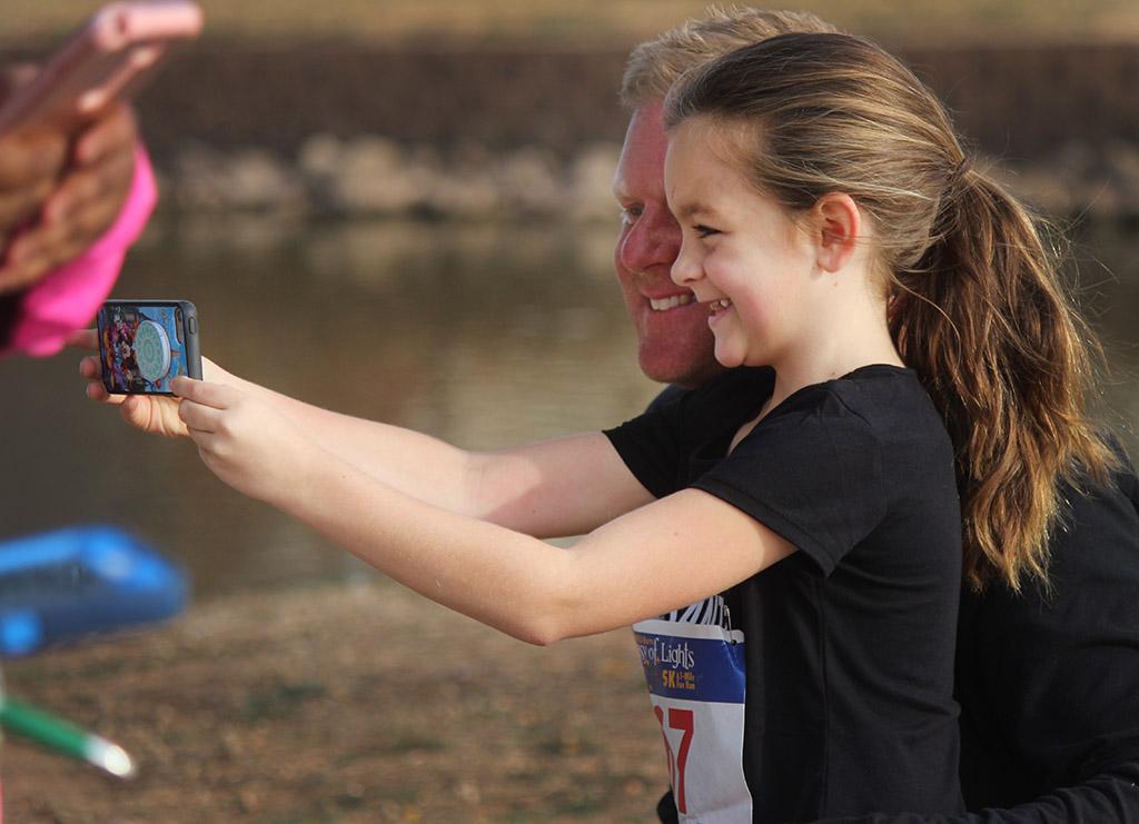 Harper Gillen, 1 mile participant, takes a selfie with her dad Ryan Gillen, 1 mile participant, after finishing the Fantasy of LIghts 1 mile event, Dec. 2, 2017. Photo by Rachel Johnson