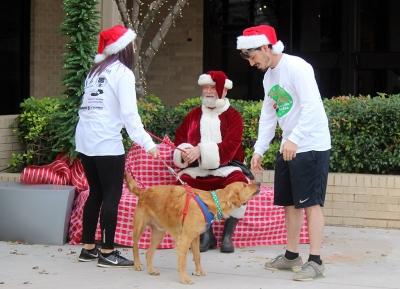 Caitlyn Cremeens, 2015 graduate, and Braden Wood, 2013 graduate, try to get a picture with their dog, Mack with Santa who was played by Wichita Falls COunty Judge Woodrow Gossom Jr. Photo by Rachel Johnson