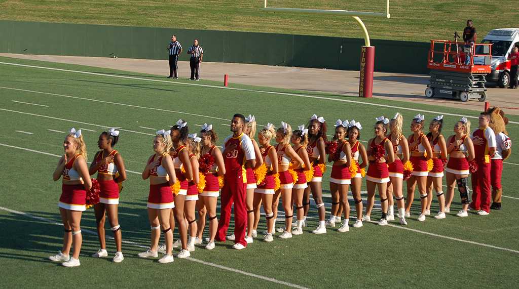 Cheerleaders stand and put their hand over their hearts during the Star Spangled Banner at the homecoming game on Saturday, Oct. 21, 2017. Photo by Shea James