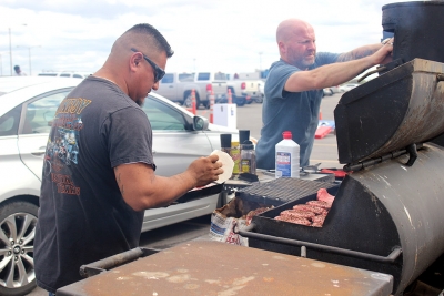 Pedro Rojo, cook for Junior League of Wichita Falls, and Robert Ross, cook for Junior League of Wichita Falls, cook for German pilots at the tailgate outside of Memorial Stadium before the Homecoming Game. Photo by Rachel Johnson