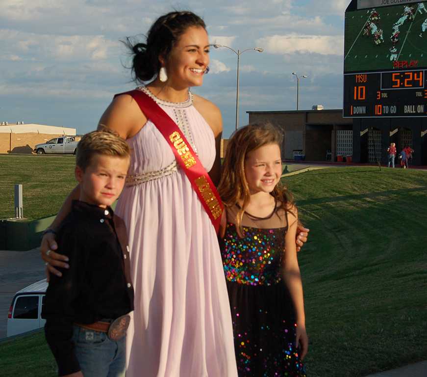 Miranda Rodriguez, education senior, poses with the two kids that escorted her onto Memorial Stadium for the announcement of Homecoming King and Queen on Oct. 17, 2017. Photo by Shea James