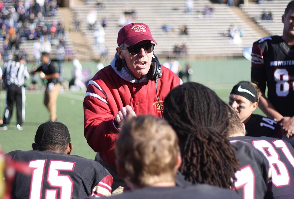 Head Football Coach Bill Maskill gives the team a pep talk during the second half of the NCAA II Round One Playoffs game during a time out called at Memorial Stadium. Photo by Rachel Johnson