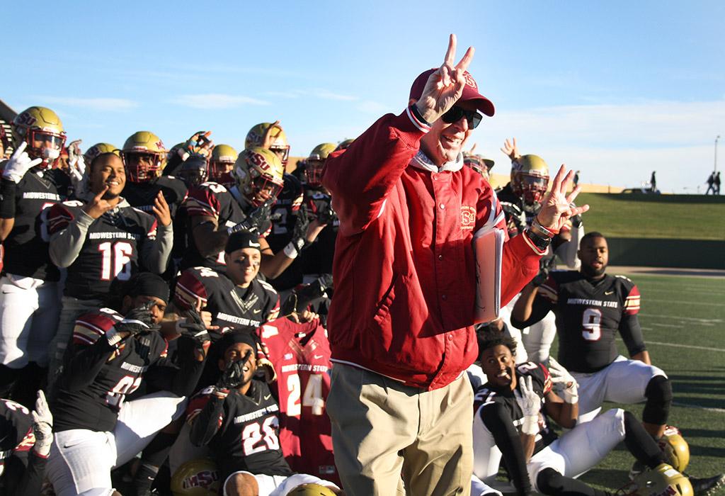Head Football Coach Bill Maskill holds up the number 24 in honor of the recently deceased player Robert Grays, for a group photo after MSU beat University of Sioux Falls 24-20 in Round One NCAA II Playoffs game at Memorial Stadium. Photo by Rachel Johnson