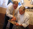MWSU Vice President for University Advancement and Public Affairs Howard Farrell gives a photo to gubernatorial candidate Greg Abbott at Stanley's BBQ in Wichita Falls, Texas Oct. 25, 2015. The photo was from a yearbook of Abbott's mother. Farrell said, "Am I going to remind the possible governor of his connection to Midwestern State University? You bet." Abbott said he was going to put the photo on his wall. Photo by Bradley Wilson