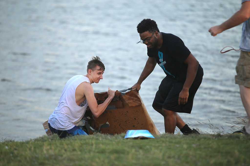 Luke Sanders, psychology senior, and Aaron Devaul, psychology senior, pull their boat from the water after  the homecoming cardboard boat race on Sikes Lake Oct. 20, 2017. Photo by Bradley Wilson