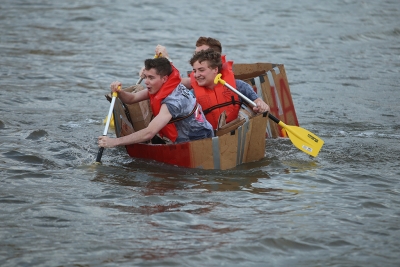 Casey Albrikes, radiology freshman, Zander Leary, math freshman, and Josh Gribble, biology sophomore, paddle the Residence Hall Association boat at the homecoming cardboard boat race on Sikes Lake Oct. 20, 2017. Photo by Bradley Wilson