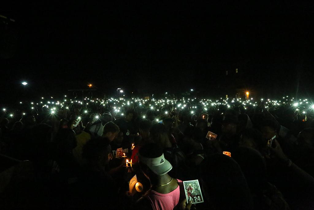 Students hold up flashlights at the candlelight vigil remembering Robert Greys on Jesse Rogers Promenade on Sept. 21. Photo by Elias Maki