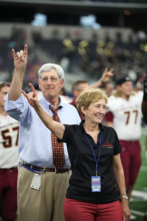 Charlie Carr, athletic director, and Suzanne Shipley, University president, throw up the "stang sign" while the band performs the alma mater during the end of Eastern New Mexico University vs. MSU game at AT&T Stadium, Sept. 19. Photo by Francisco Martinez