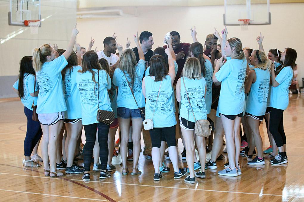 Chi-Omegas surround the winning team, Fab 5, after the championship game and do their sorority chant around them. The Fab 5 beat Sticky Bandits 27-20 in the Chi-Omega Basketball Tournament, Swishes for Wishes, Saturday, March 28, 2015. Photo by Rachel Johnson