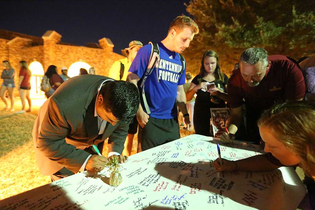 Wichita Falls Mayor Stephen Santellana, Jacob Sherrill, a respiratory therapy, and Provost James Johnston sign the poster for injured football player.