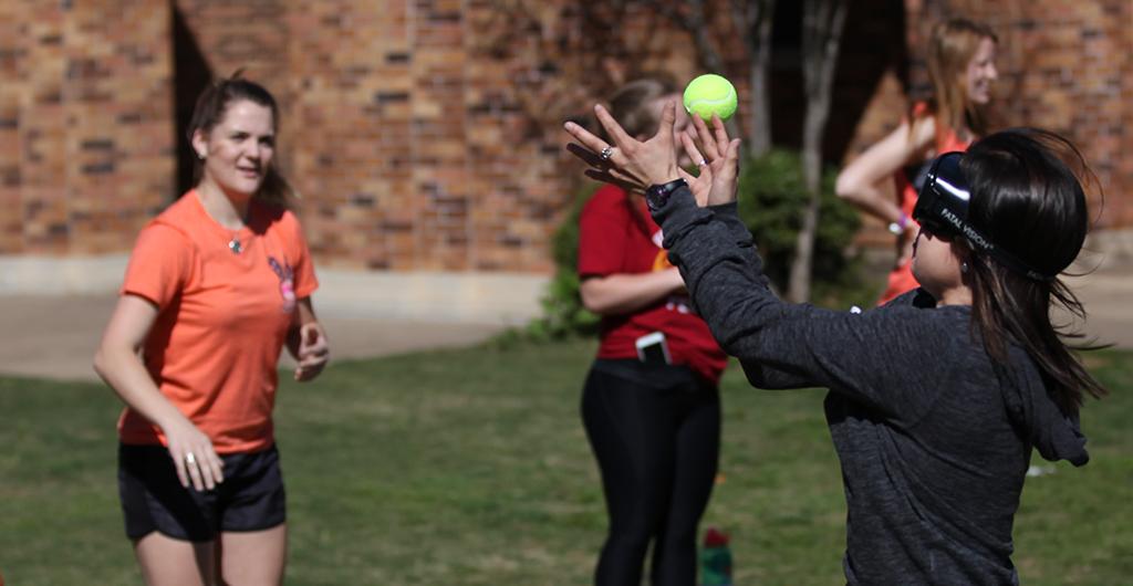 Nicole Buchanan, education junior, attempts to catch a tennis ball wearing drunk goggles during the Drunk Goggle Relay on March 15, put on by housing for Alcohol Awareness Month. Photo By Dewey Cooper