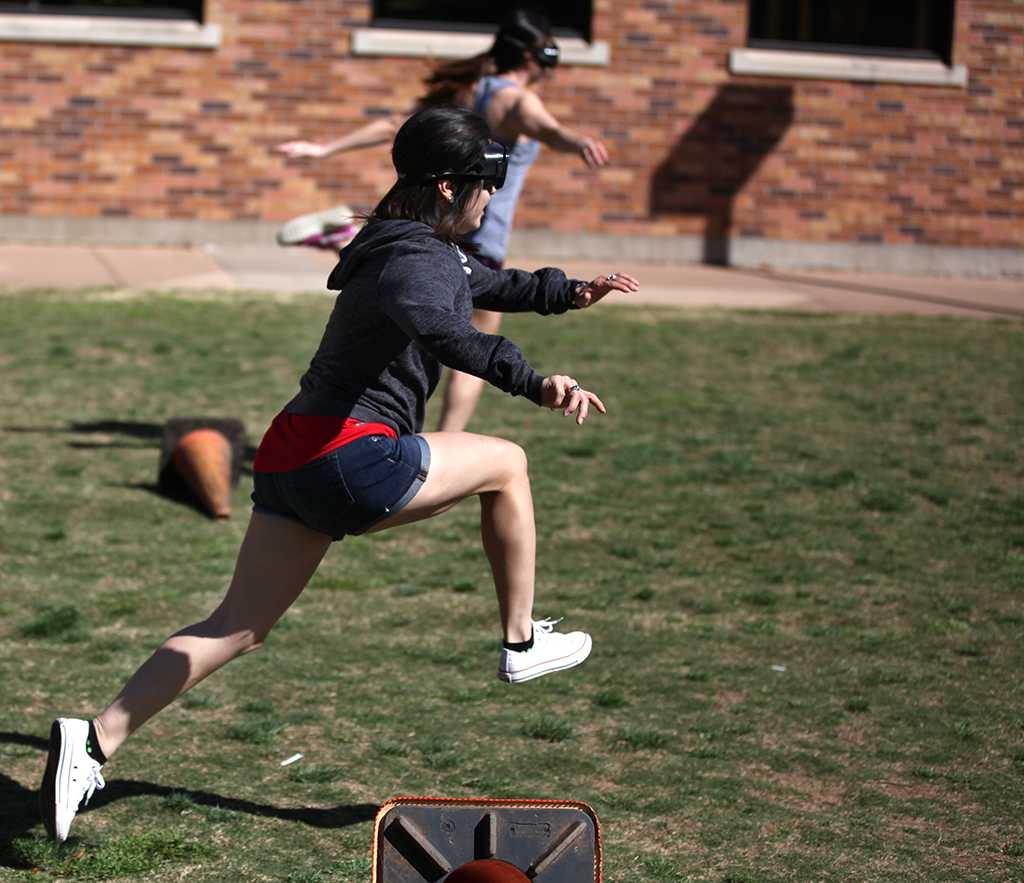 Nicole Buchanan, education junior, jumps over a cone wearing drunk goggles during the Drunk Goggle Relay on March 15, put on by housing for Alcohol Awareness Month. Photo By Dewey Cooper