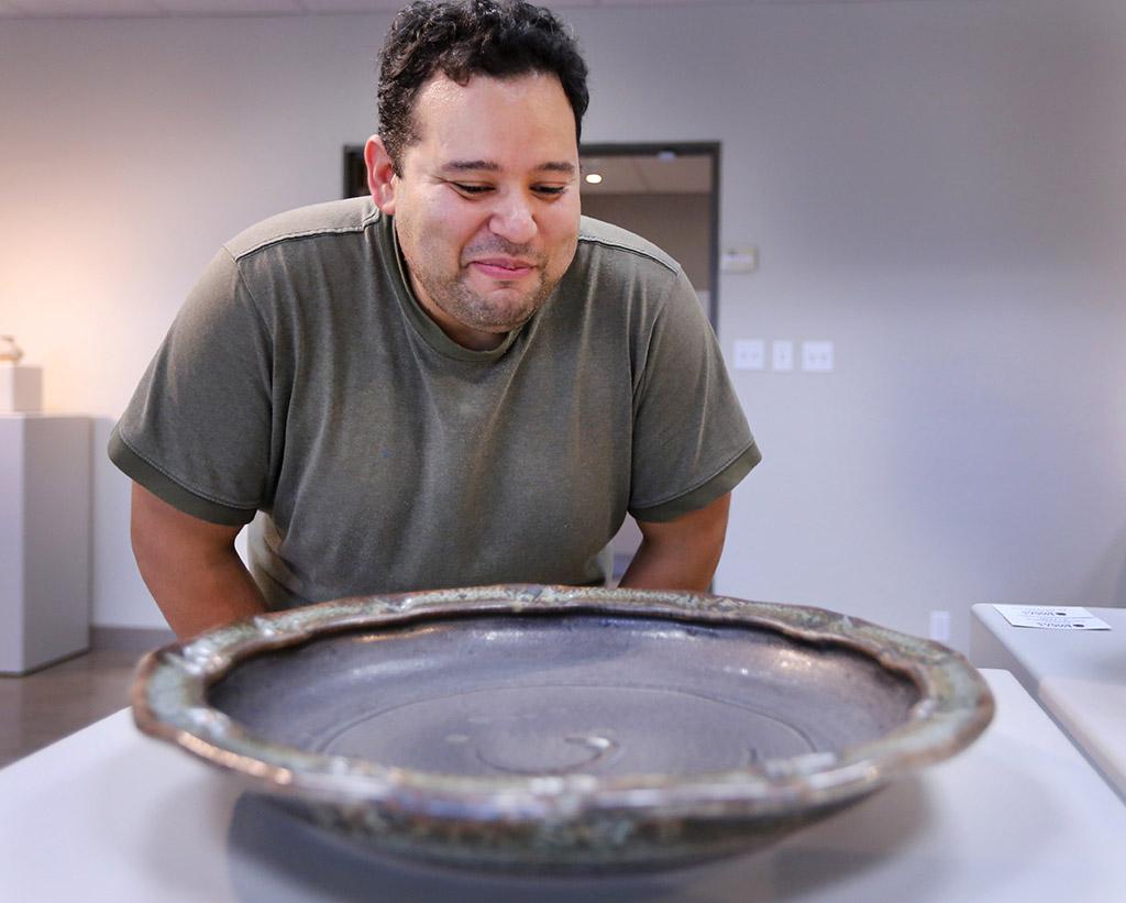 Alberto Veronica, creator of "Peachy Bowl" piece, admires other artist's bowls during the Empty Bowls Gallery in the Wichita Falls Museum of Art at MSU Oct. 5. Photo by Rachel Johnson