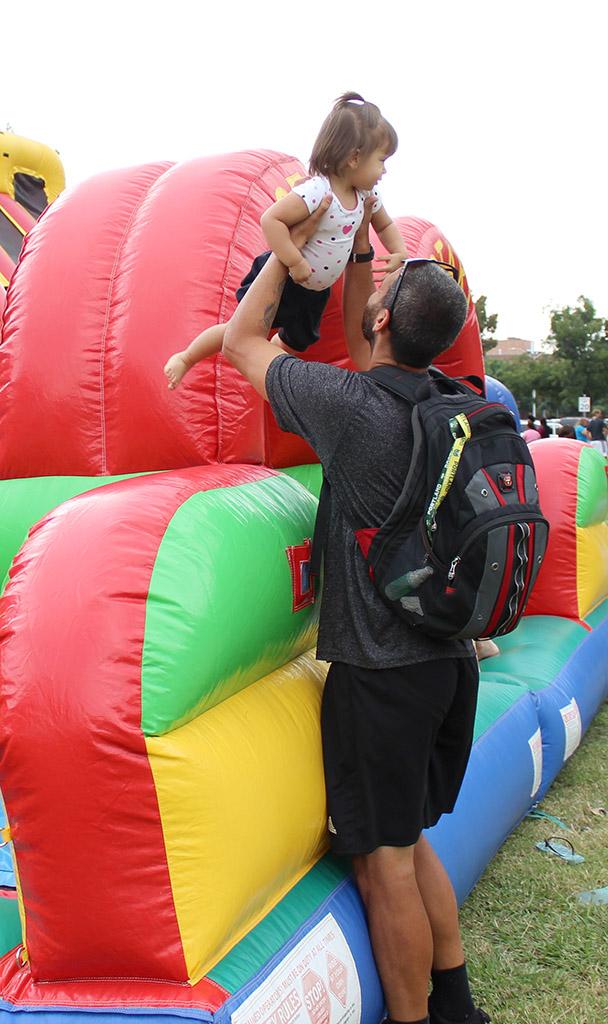 Marcel Campolina, excersize physiology graduate student, picks up his daughter, Eva Campolina, after she slides down one of the inflateable obstacle courses set up in the Quad by Dillard on Family Day, Sept. 26. Photo by Francisco Martinez