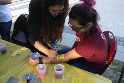Xochit Cruz, political science sophomore, gets a temporary tattoo at the spring Finals Frenzy on the Jesse Rodgers Promanade on May 4. "Volunteering with my sorority sisters makes it fun, we're all just having a good time," Cruz said. Photo by Timothy Jones