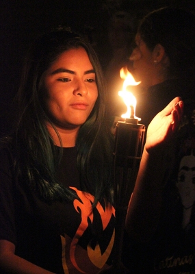 Conney Vargas, marketing senior, holds her hand infront of the flame as she walks towards to front of the parade being one of the first to get her torch lit at the Torchlight Parade tradition apart of MSU Homecoming, Thursday, Oct. 19, 2017. Photo by Rachel Johnson