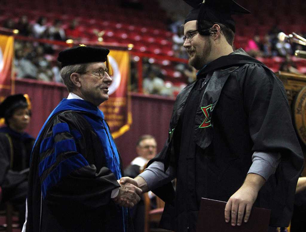 Jesse Rodgers, university president, shakes every students hand as they walk the stage at Midwestern State University fall graduation, Dec. 13, 2014 in Wichita Falls, Texas. Photo by Rachel Johnson