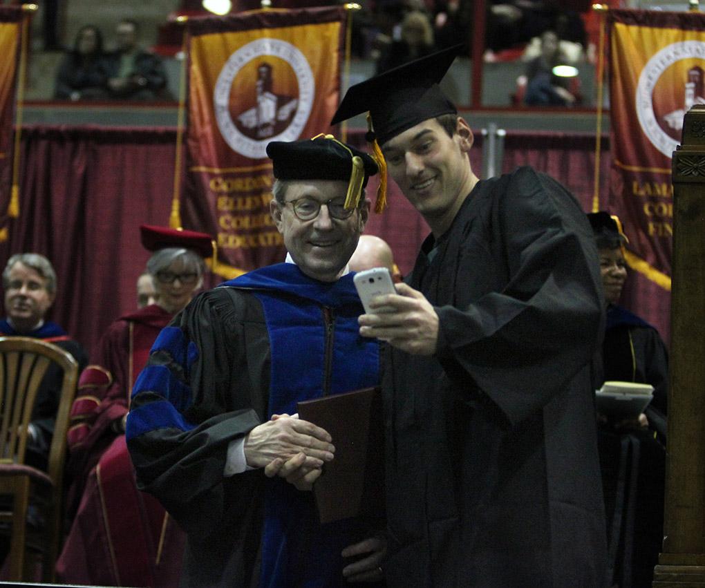 Tyler Hackbarth, computer science, takes a selfie with Jesse Rodgers, university president, at Midwestern State University fall graduation, Dec. 13, 2014 in Wichita Falls, Texas. Photo by Rachel Johnson