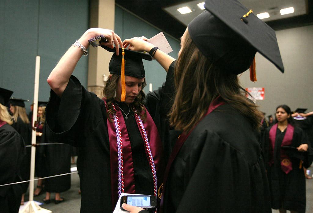 Mae Johnson, nursing, gets help from Deborah Roucloux, nursing, to fix her cap while waiting for Commencement to start at the MPEG, May 14. Photo by Rachel Johnson