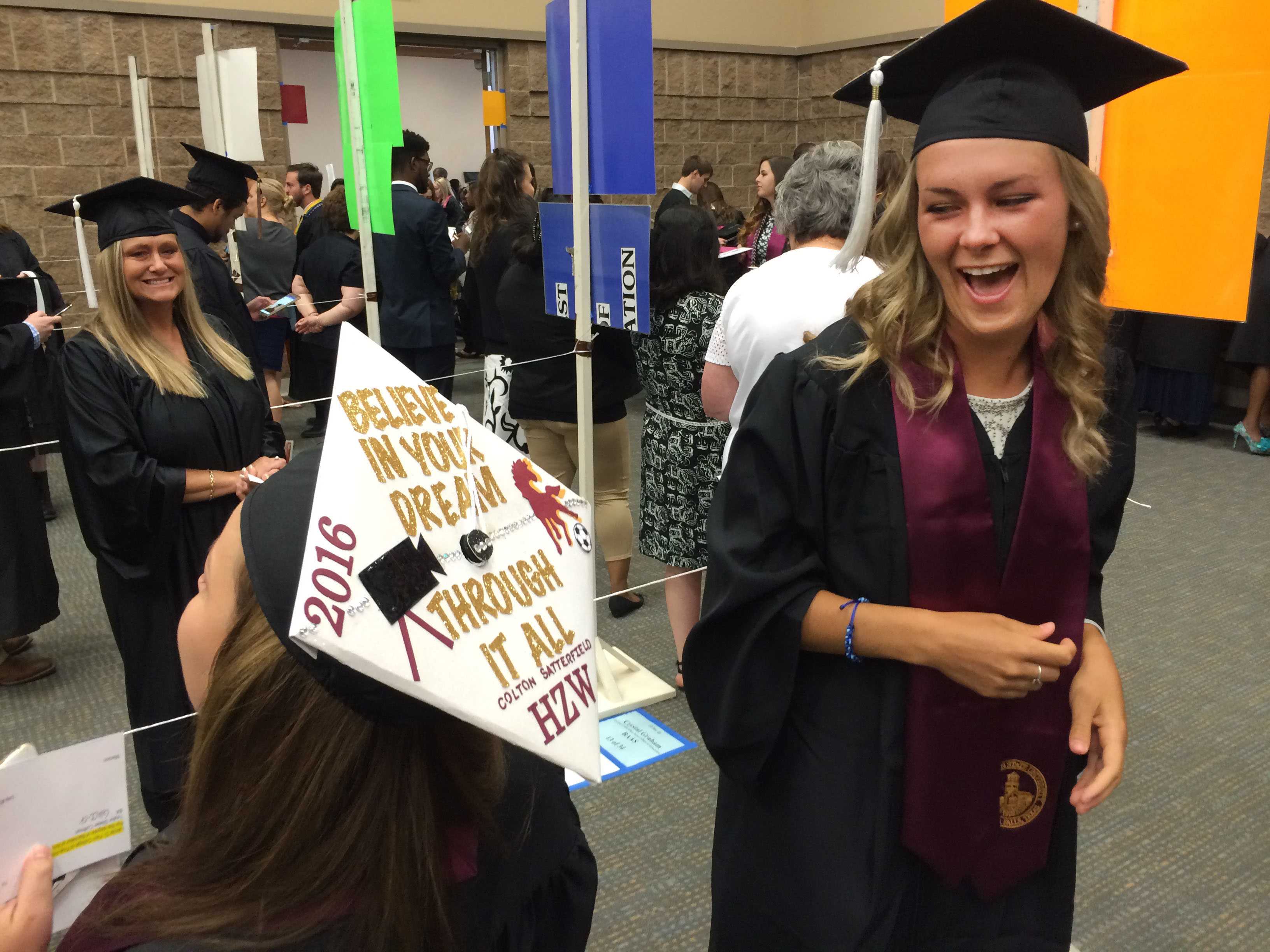 Taylor Coffman, mass communication, chuckles while reading Harley Warrickâs mortar board at Midwestern State University graduation, May 14. This was the first year graduates have been allowed to decorate their hats. Photo by Bradley Wilson