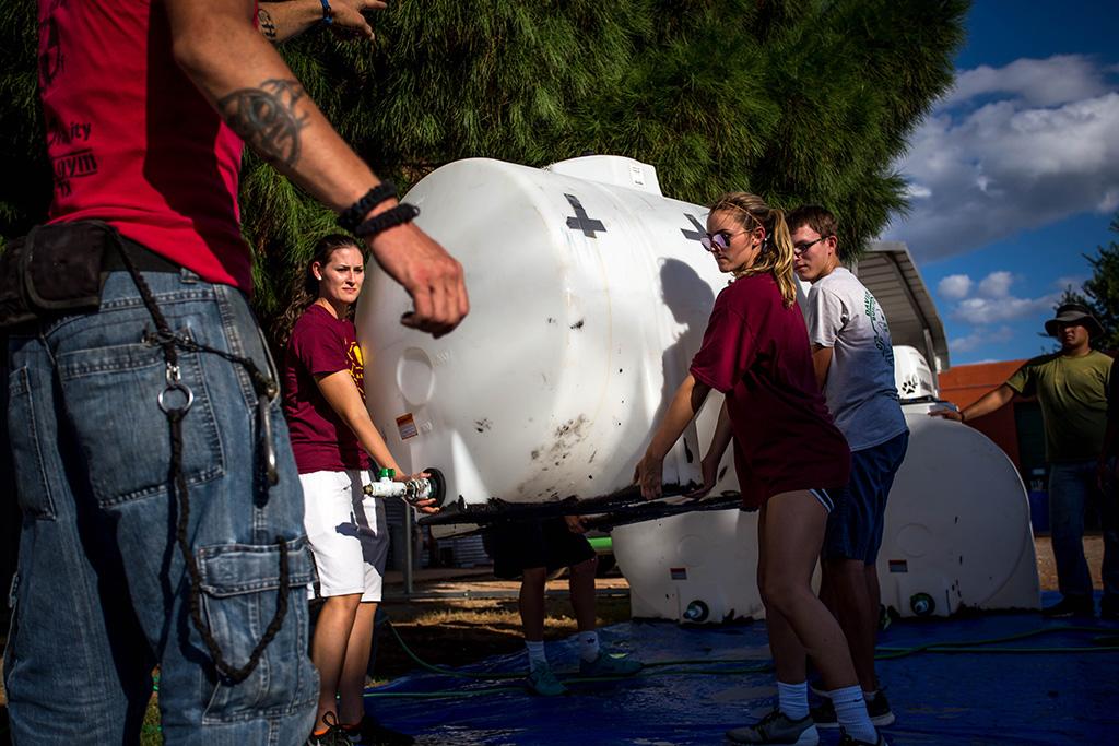 Jenifer Arbuckle, mechanical engineering senior and women's basketball team member, helps to clean tubs to be used for water at the Hotter N Hell race the next day. Photo by Izziel Latour