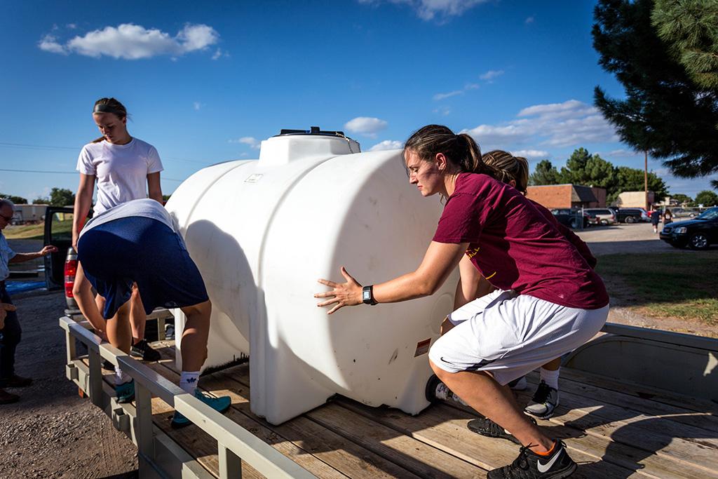 Jenifer Arbuckle, mechanical engineering senior and women's basketball team member, helps to clean tubs to be used for water at the Hotter N Hell race the next day. Photo by Izziel Latour