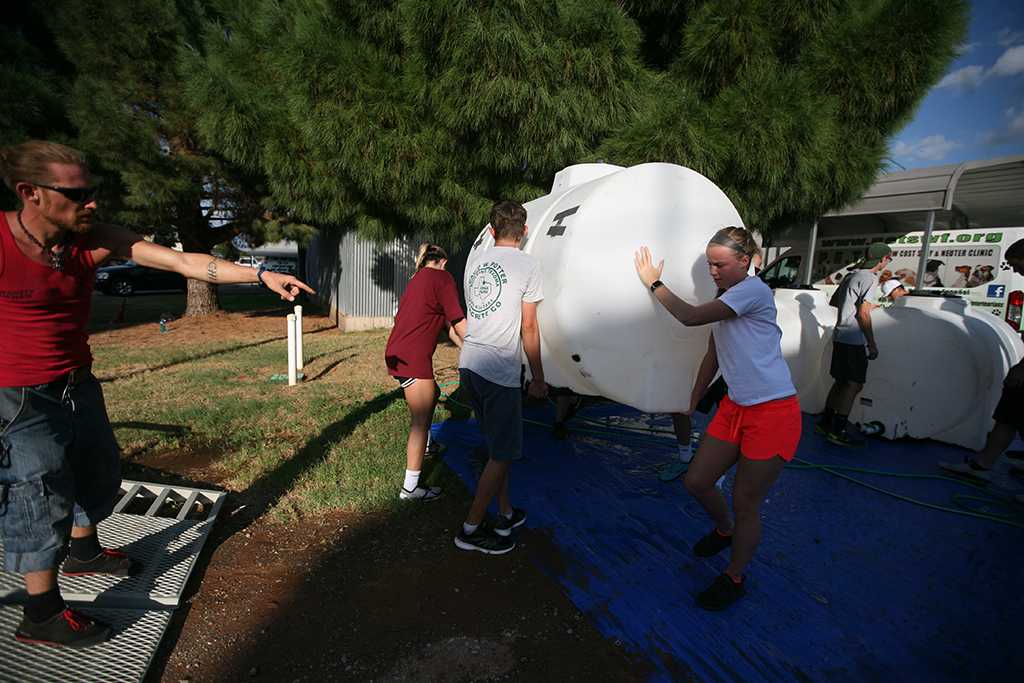Members of the Midwestern State University women's basketball team clean tubs to be used for water at the Hotter N Hell race the next day. Photo by Bradley Wilson