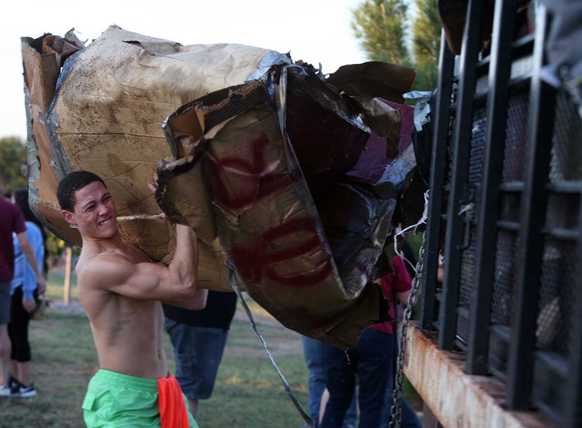 Shane Jones, business freshman, lifts a trashed boat onto the collection truck at the cardboard boat race in Sikes Lake Oct. 24, 2014. Photo by Bradley Wilson